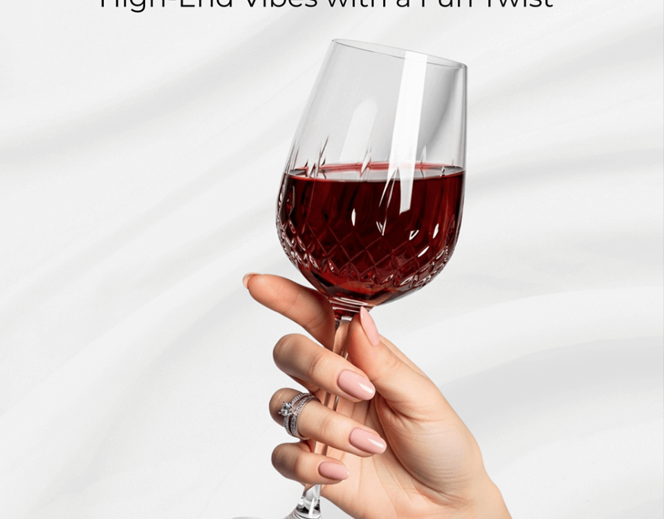 A hand with manicured nails holding a wine glass, set against a white background.